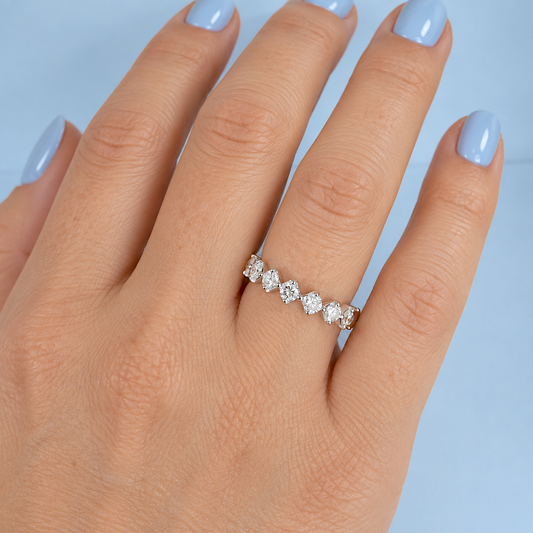 Alliance américaine en diamants et or blanc 18K, portée à la main, gros plan sur fond bleu clair