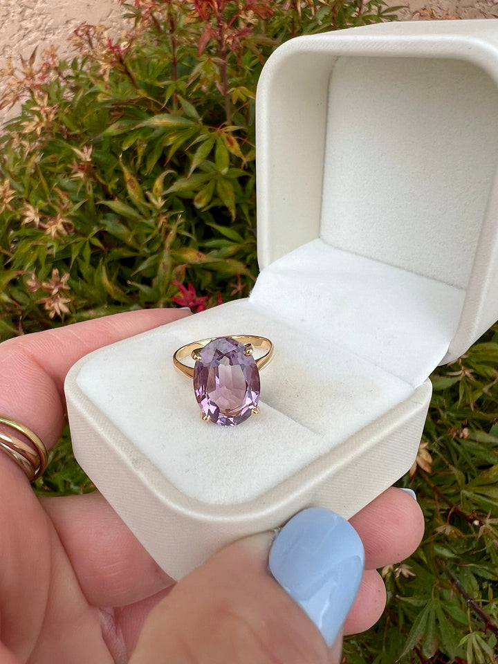 Bague solitaire améthyste ovale or jaune 18K dans son écrin crème ouvert, tenu en main, feuillage d'érable du Japon