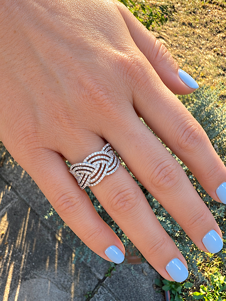 Bague diamants contemporaine en or blanc 18 carats portée au doigt, ongles bleu pastel, au jardin