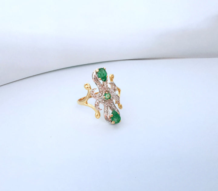Vue de dessus d'une bague marquise émeraudes et diamants en or deux tons sur fond blanc