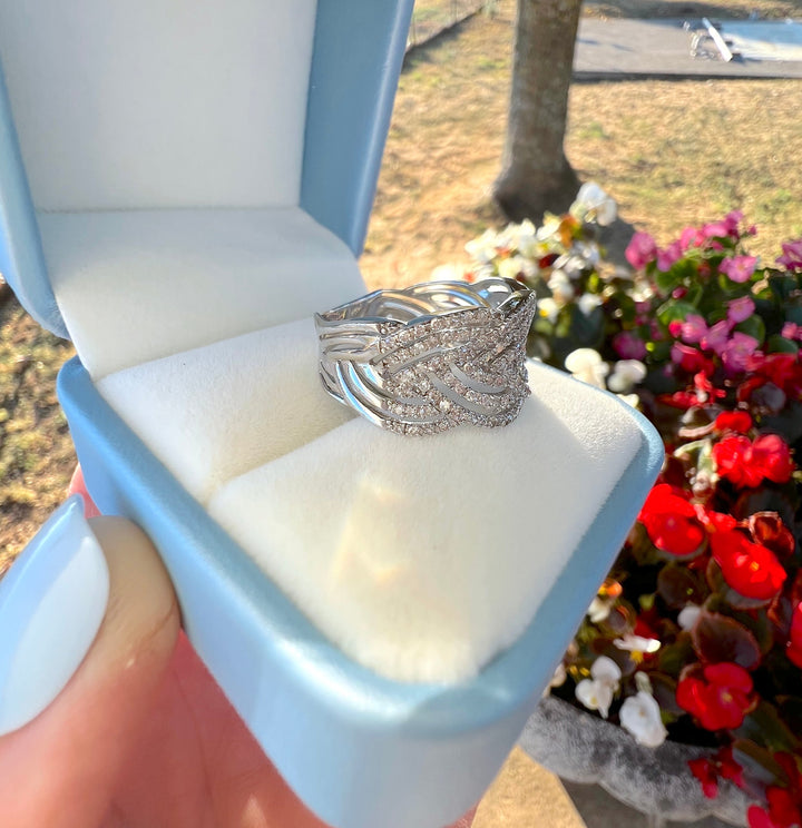 Bague de joaillerie de seconde main en or blanc 18K et diamants, en écrin ouvert devant des fleurs