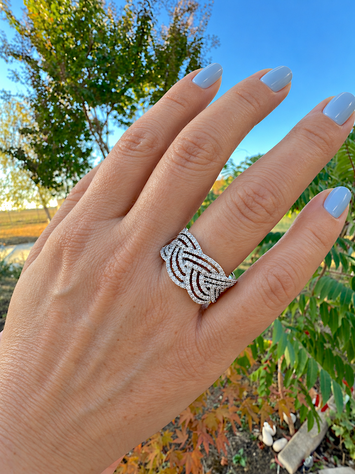 Bague diamants en or blanc 18K portée au doigt, ongles bleu pastel, ciel bleu en arrière-plan