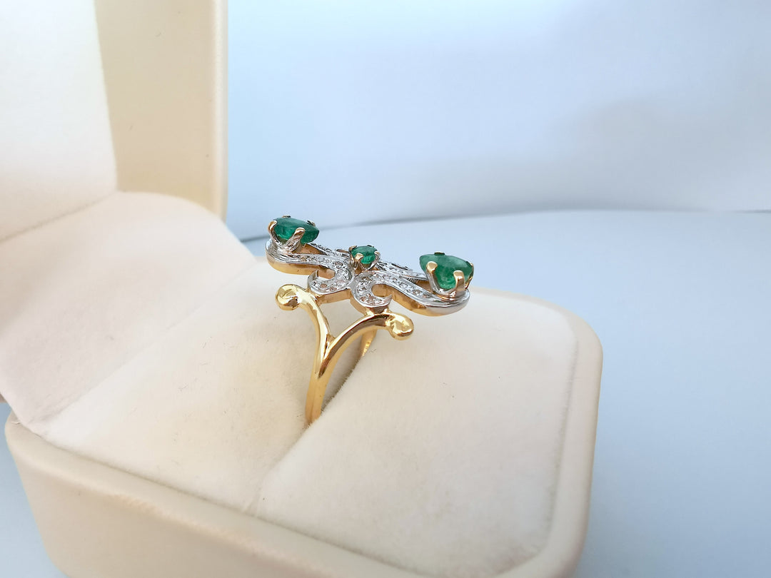 Bague marquise or deux tons émeraudes et diamants présentée dans son écrin, vue en angle