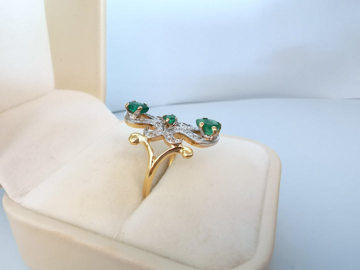 Bague marquise or deux tons émeraudes et diamants présentée dans son écrin, vue en angle