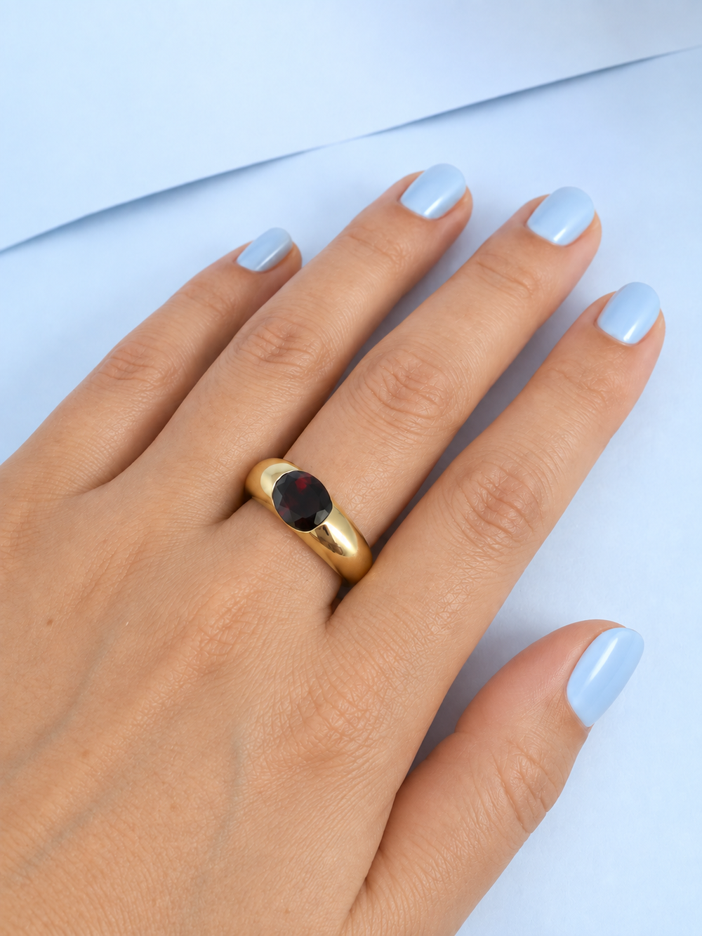 Bague grenat jonc or jaune 18K bijou femme portée macro sur fond bleu