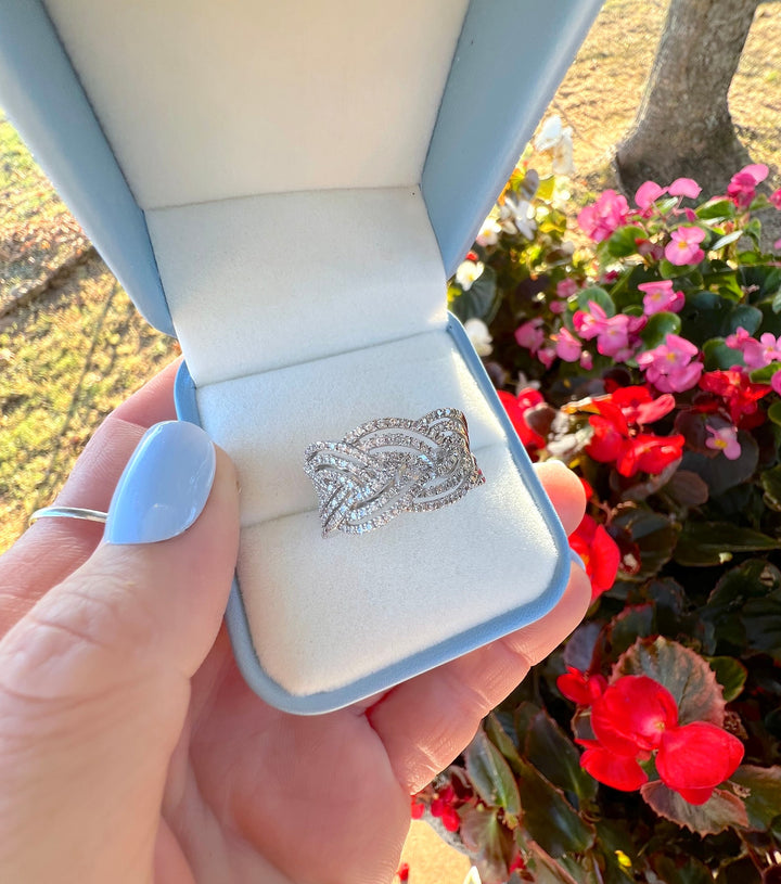 Bague de luxe de seconde main, pavage de diamants et tressage en or blanc, dans son écrin tenu à la main