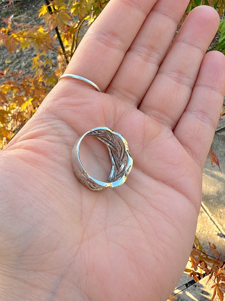 Bague tressée diamants or blanc 750 de seconde main posée dans la paume d'une main, intérieur de l'anneau visible