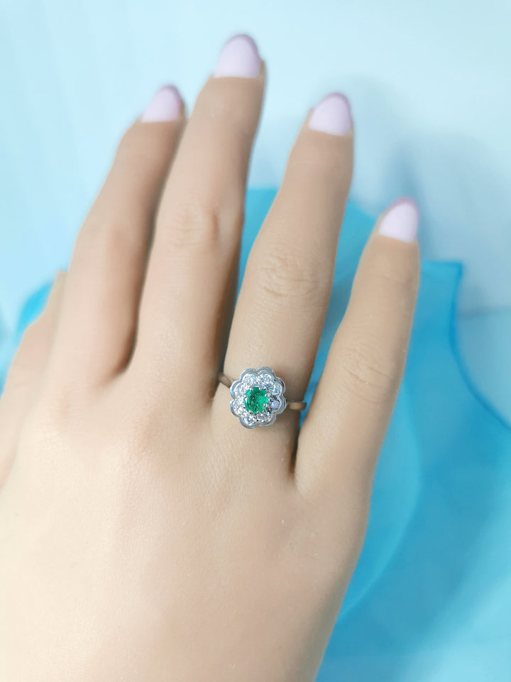 vue de face sur main bague marguerite emeraude entourée de diamants joaillerie circulaire seconde main