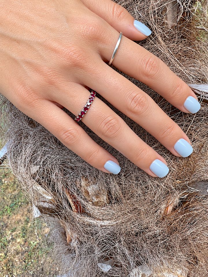 Alliance rubis en or gris 18 carats portée à la main, en gros plan, avec un anneau fin en argent