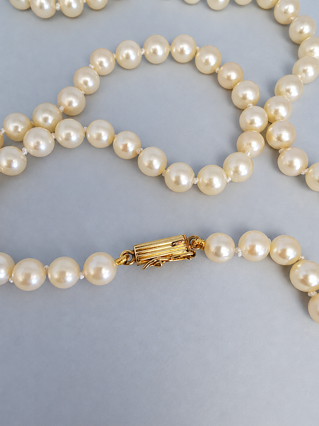 Gros plan macro du fermoir en or jaune 18K sur le collier de perles de culture, bijou de luxe de seconde main