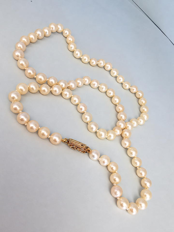 Collier de perles de culture disposé en boucles sur fond clair, fermoir en or visible, joaillerie de luxe pour femme