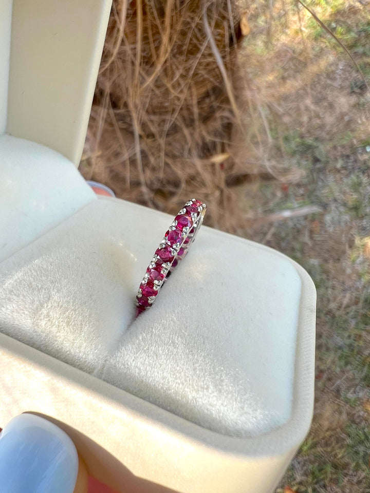 Alliance rubis or gris 18K de profil, debout dans un écrin en velours, vue sur les griffes et les rubis
