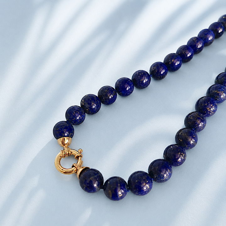 Gros plan du fermoir en or jaune 18 carats sur un collier de perles en lapis-lazuli, bijou neuf