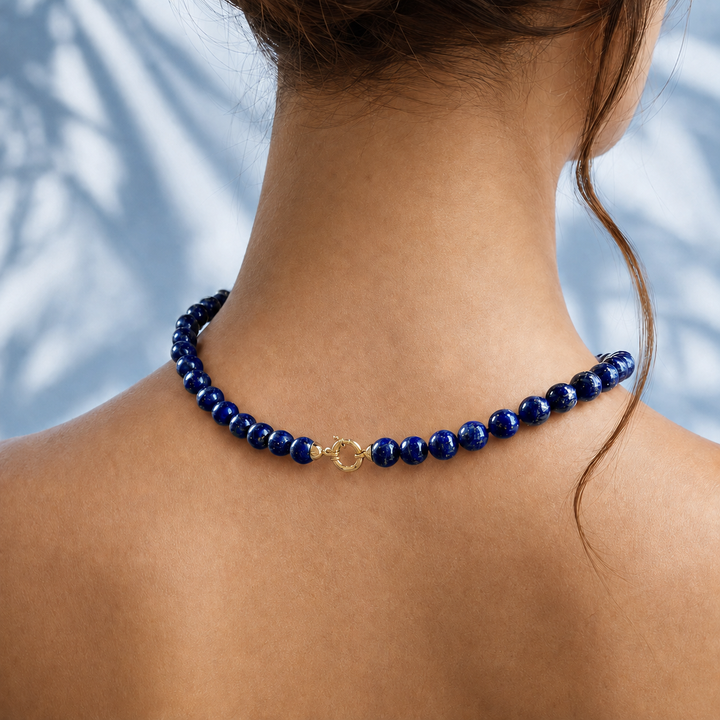 Collier de perles en lapis-lazuli porté sur la nuque, fermoir en or jaune 18 carats visible, bijou neuf